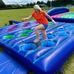 ASSAULT COURSE INFLATABLE POT HOLES hire with a woman running through at a corporate team build event