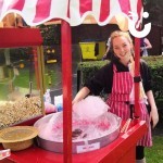 Candy Floss And Popcorn On A Cart 2Hire with a fun expert smiling and making fresh candy floss at an outdoor family fun day