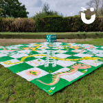 Giant Snakes and Ladders mat and dice set up on the grass