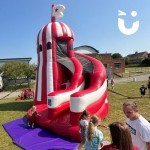 Inflatable Helter Skelter Slide ata corporate family fun day with adults and children milling around