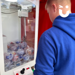 George using the Prize Crane Grabber to pick up a plastic ball with chocolates inside