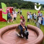 Rodeo Bull At A Fun Event with a crowd watching a man cling on!